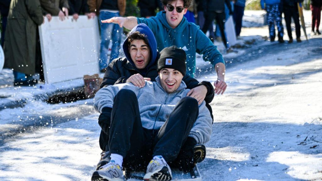 Three young men sled down a rare snowy street in Tallahassee, Florida on Jan. 22.