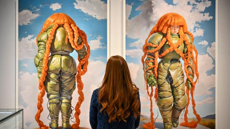 A woman looks at two AI images created by Holly Herndon and Mat Dryhurst